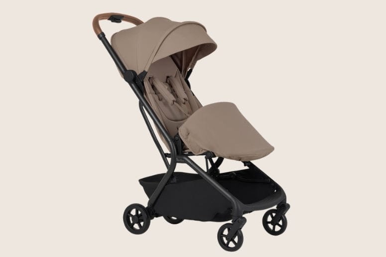 A beige and black stroller sits centered against a beige background, showcasing its sleek design and practical features.