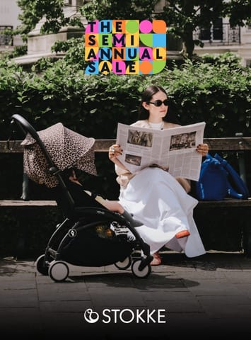 Woman reading newspaper on park bench next to a Stokke Yoyo stroller with leopard print canopy