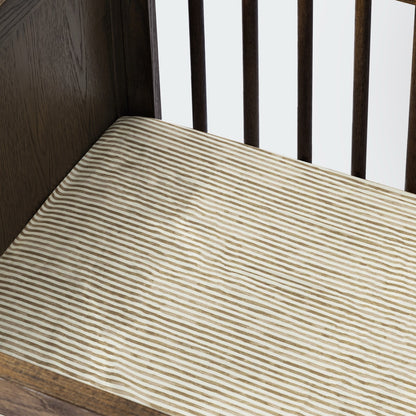 Babyletto crib mattress with tan and white striped fitted sheet