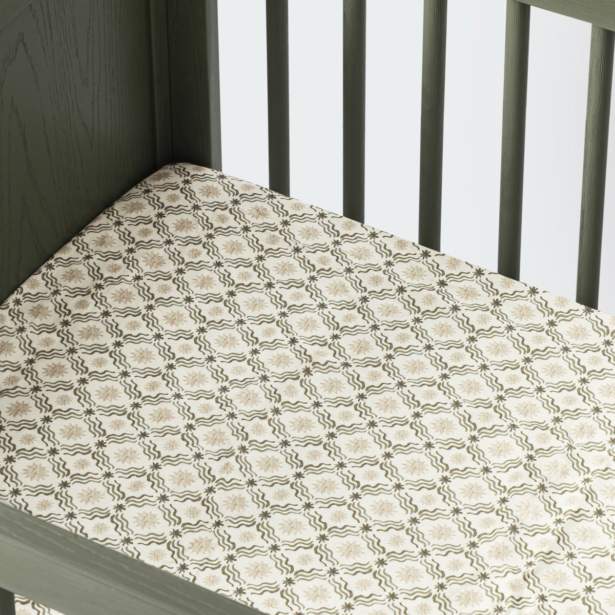 Babyletto crib sheet with a beige and olive green star and wave grid pattern