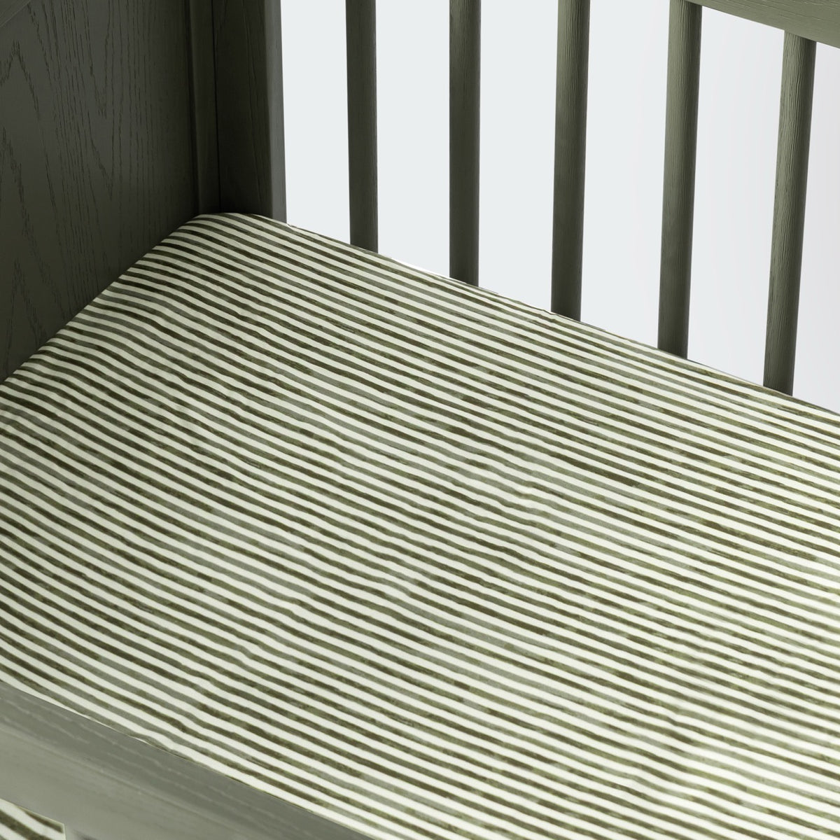 Babyletto crib mattress with green and white striped fitted sheet