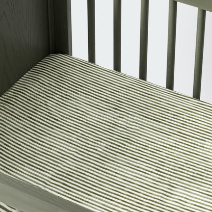 Babyletto crib mattress with green and white striped fitted sheet