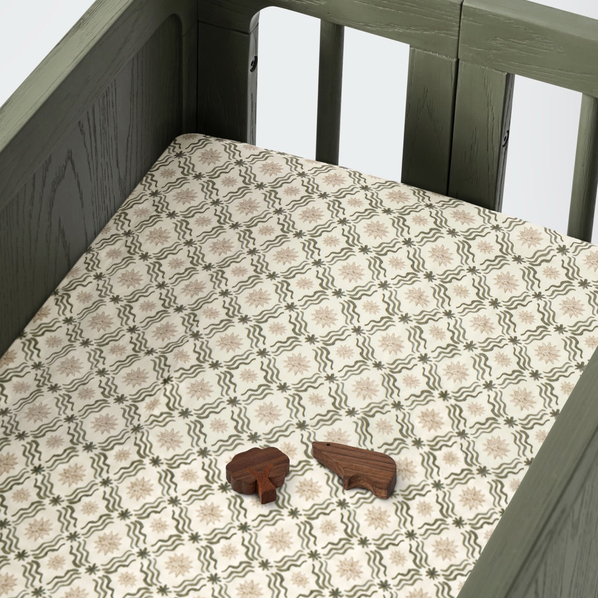 Babyletto crib sheet with star and wave pattern and two wooden animal toys