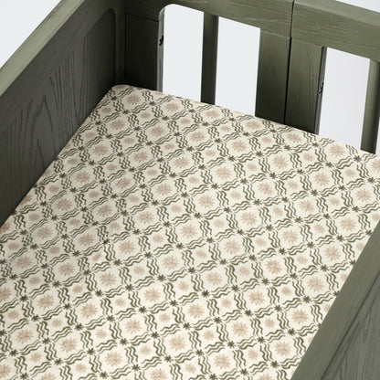 Babyletto crib mattress with cream sheet featuring a green wavy line and star pattern