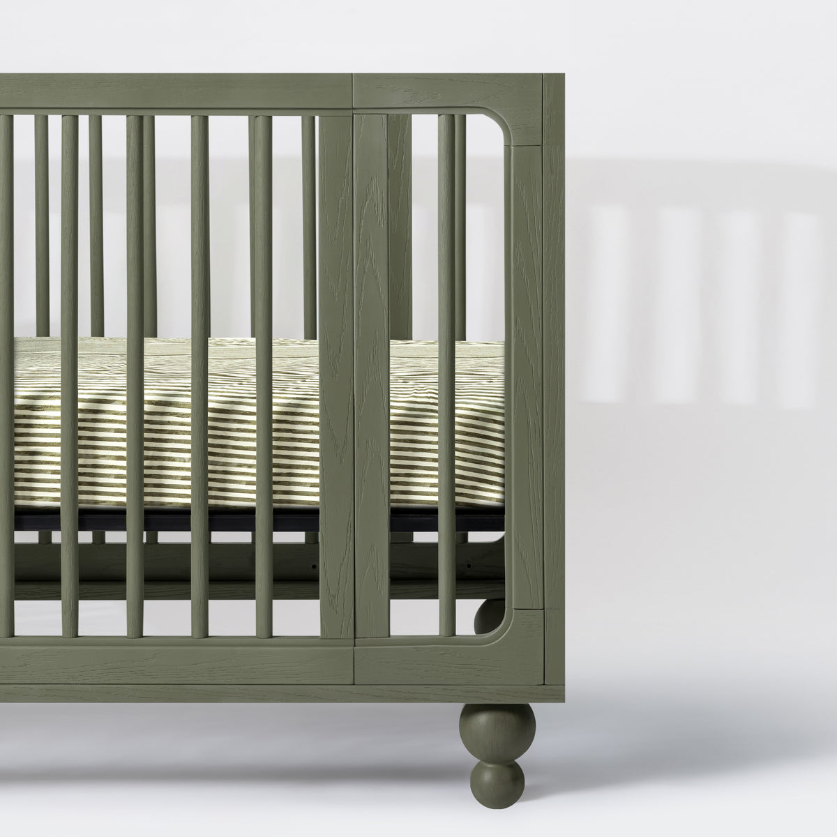 Babyletto olive green wooden crib side view with striped mattress sheet