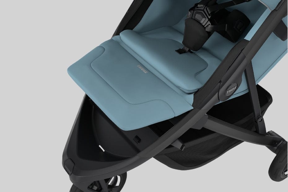 Light blue Thule stroller seat with black frame, five-point harness, and storage basket, angled view on neutral background.