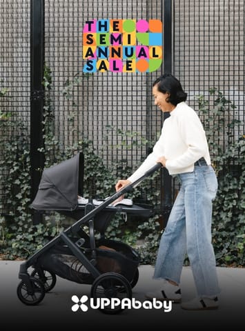 Person pushing a black UPPAbaby stroller with a semi annual sale graphic