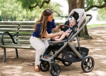 Woman sitting on a park bench adjusting a baby in a UPPAbaby Vista V2 stroller