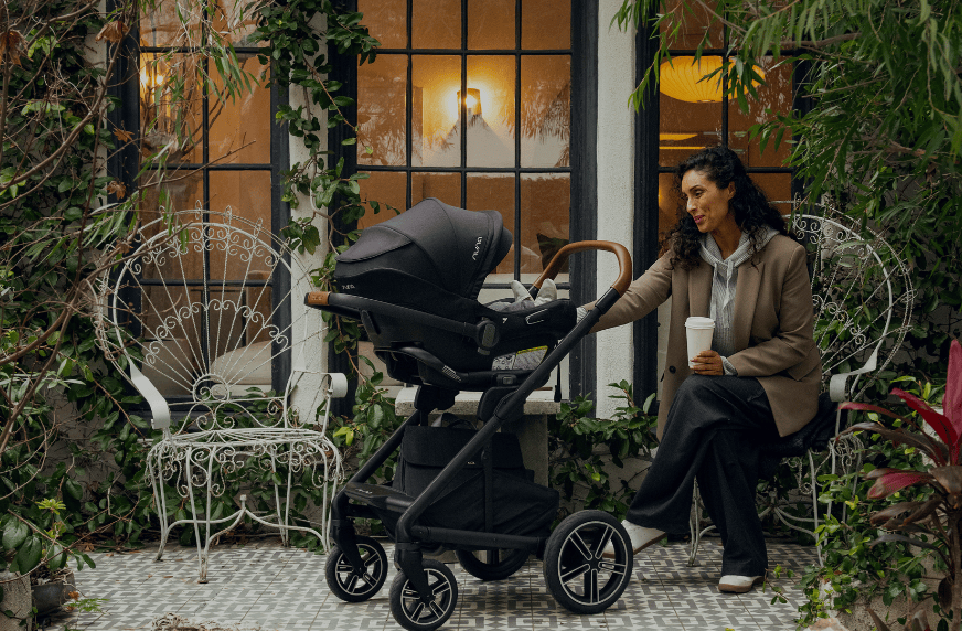 Outdoor scene shows a modern high chair with black frame next to a white table.