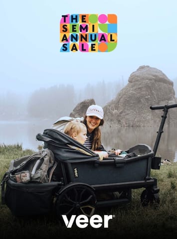 Woman and child sitting in a Veer cruiser wagon by a lake with a semi annual sale graphic