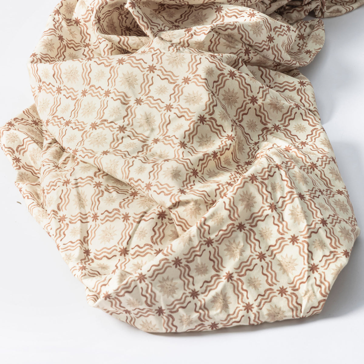 Babyletto fabric with brown wavy lines and star patterns on a cream background
