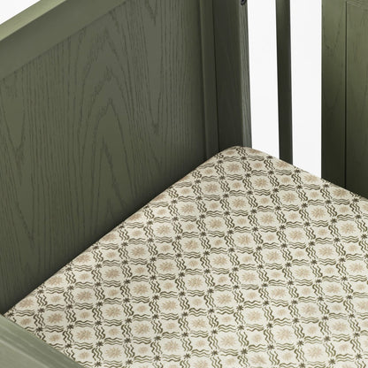 Babyletto crib with olive green wooden frame and patterned mattress sheet