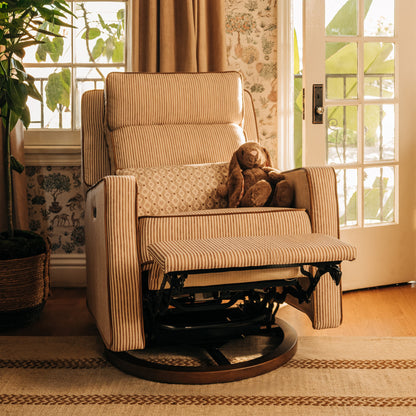 Babyletto striped recliner with footrest extended and plush toy in a sunlit room