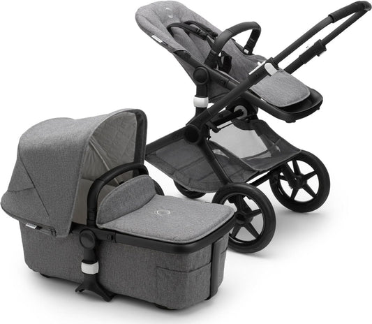 Black and grey melange Fox2 complete stroller by Bugaboo, featuring matching carrycot, textured fabric, and black frame with star-shaped wheels, shown in side view.