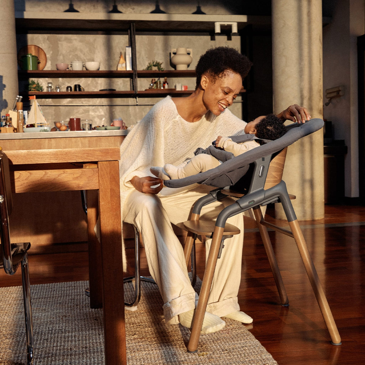 Parent interacting with baby in a Bugaboo high chair in a kitchen