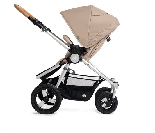 Sand-colored Bumbleride Era stroller with silver frame, checkered canopy lining, and black mesh storage basket, side view