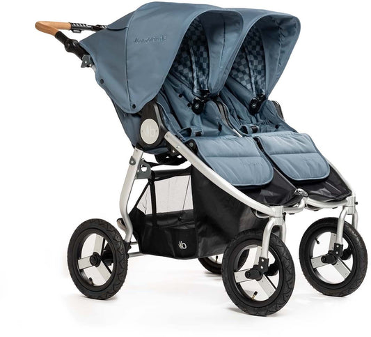 Ocean blue side-by-side double stroller by Bumbleride with silver frame, checkered canopy lining, wooden handle grip, and black mesh storage basket, front three-quarter view