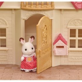 Calico Critters rabbit figure standing in the doorway of a toy house with a pink mailbox