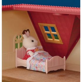 Calico Critters rabbit figure in a small pink bed with floral bedding inside a toy house