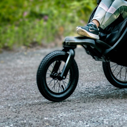 Child resting feet on the front wheel frame of a Chicco jogging stroller