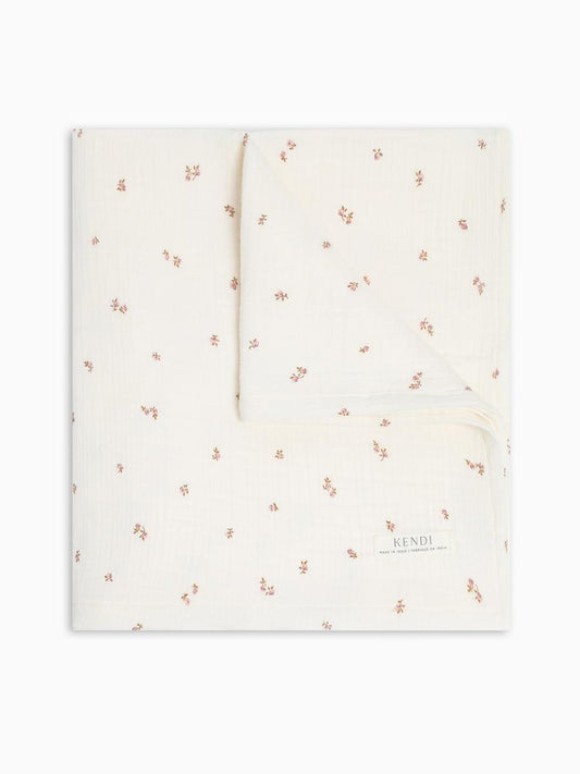 Colored Organics cream muslin blanket with small pink floral print and Kendi brand label