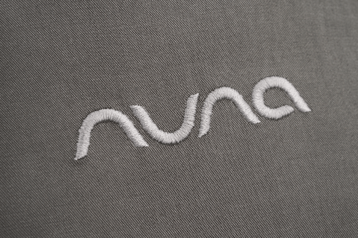 Embroidered 'Nuna' logo on a gray fabric background