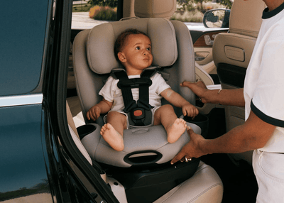 Toddler secured in a grey convertible car seat inside a vehicle