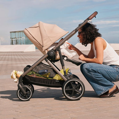Cybex Gazelle S stroller with beige canopy and storage basket containing flowers and groceries