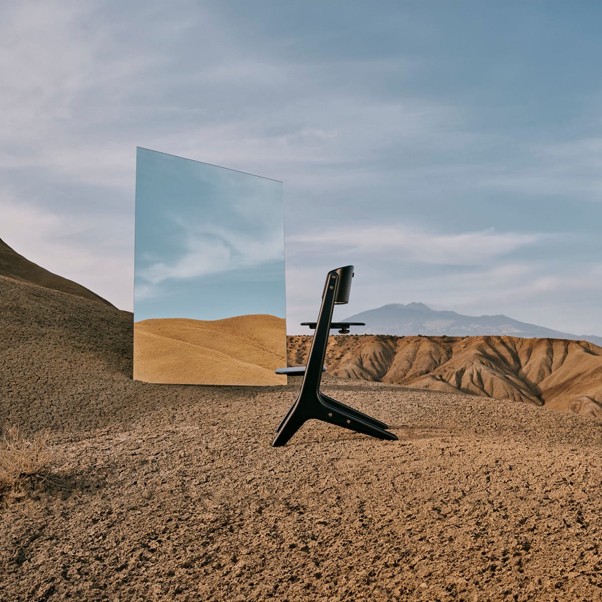 Cybex high chair standing on desert terrain next to a tall mirror reflecting the landscape