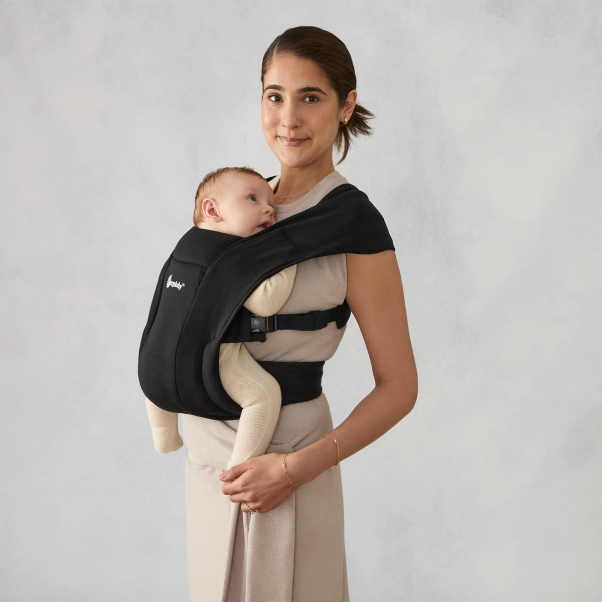Woman wearing a black Ergobaby Embrace baby carrier with an infant facing inward