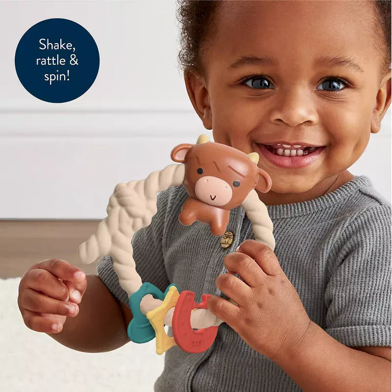 Itzy Ritzy cow rattle and teether held by a baby