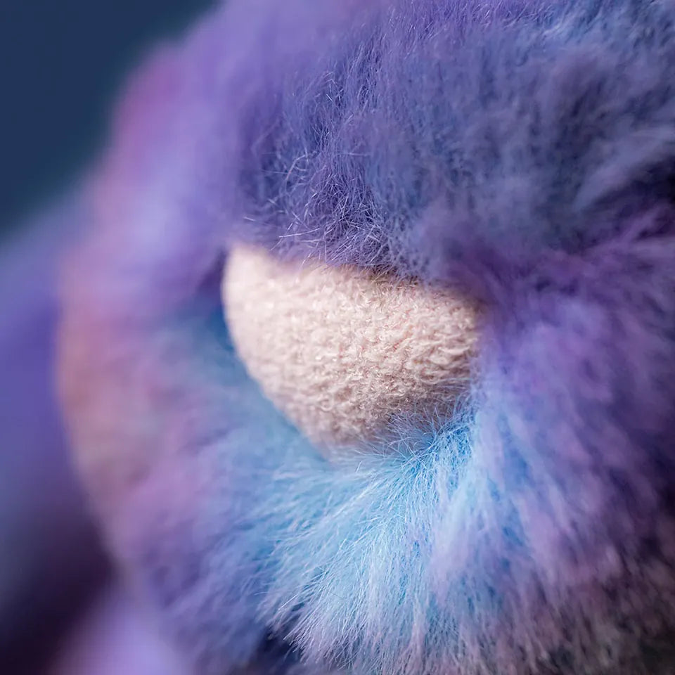Close up of purple and blue faux fur texture with a central beige fabric patch