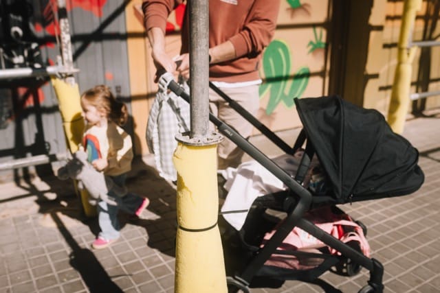 Joolz black stroller with a child holding a toy nearby