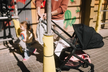 Joolz black stroller with a child holding a toy nearby