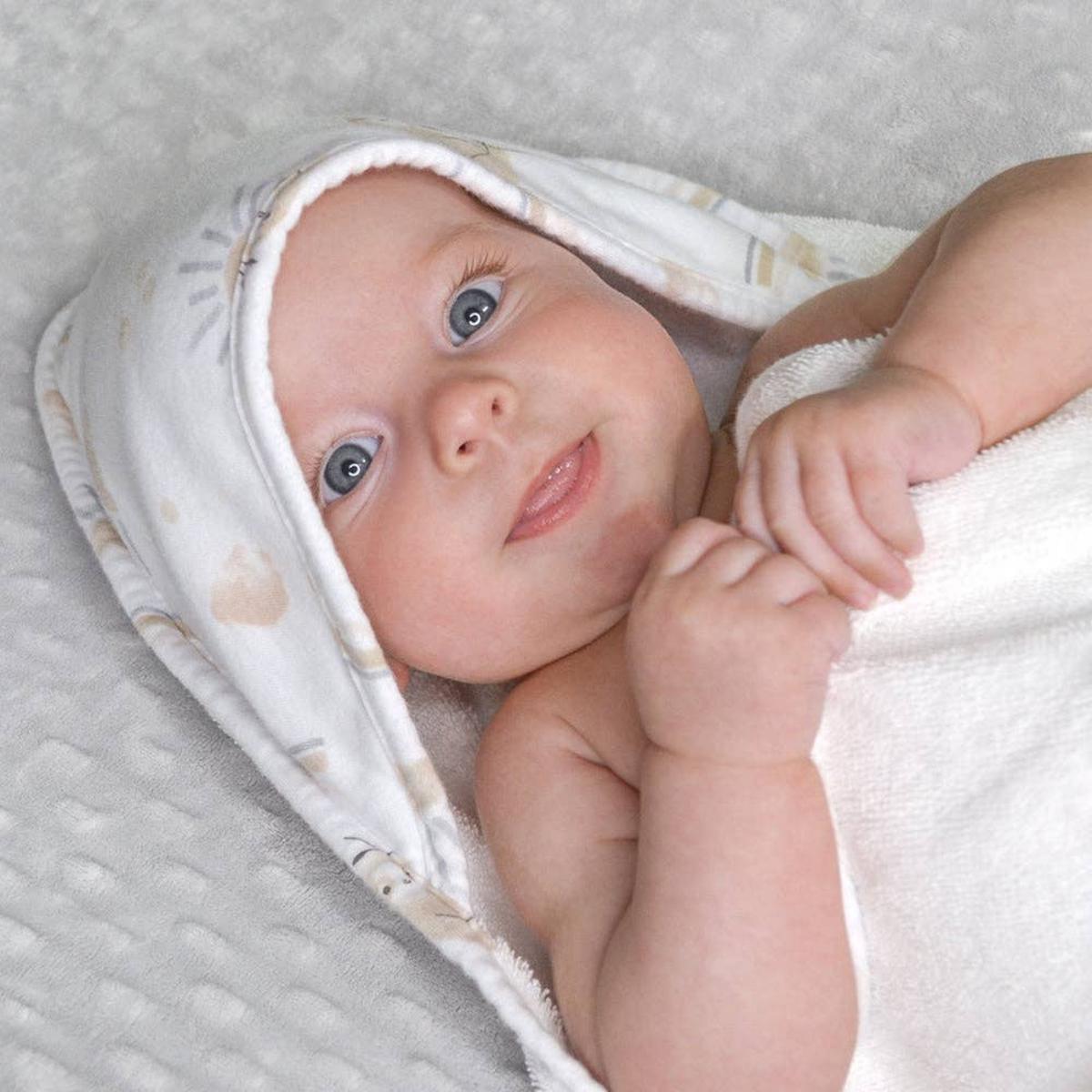Baby wrapped in a Living Textiles hooded towel with a sun print