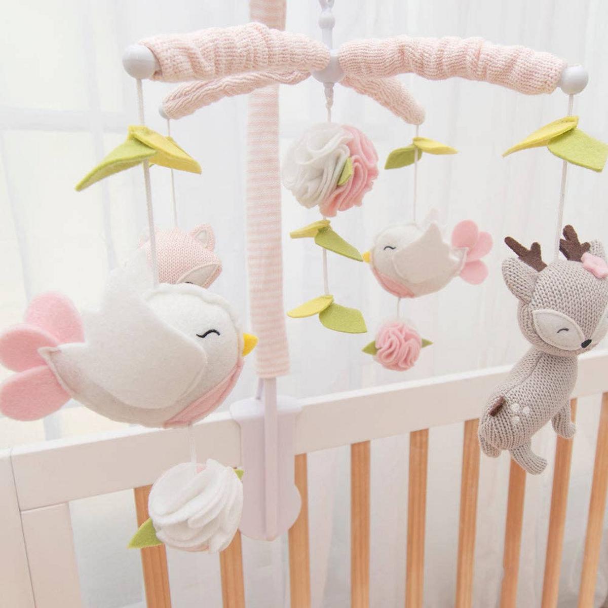 Living Textiles musical cot mobile with felt birds flowers and deer hanging over a white wooden crib