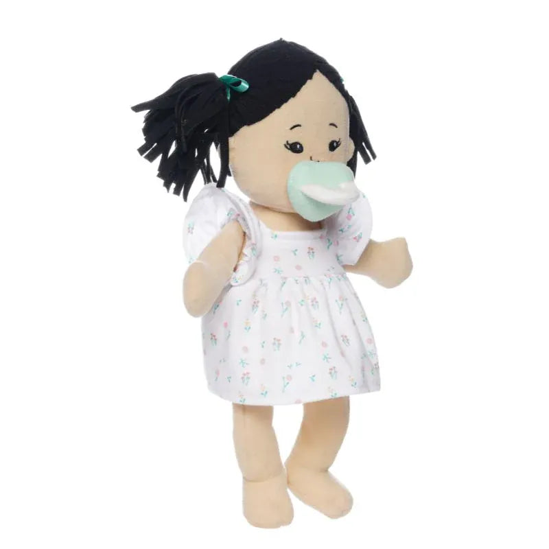Manhattan Toy soft doll with black hair in pigtails wearing a white floral dress and a mint green pacifier