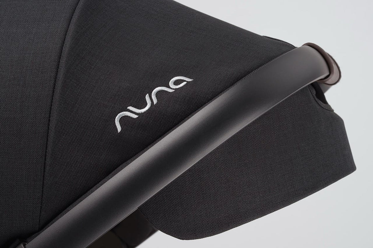 Black Nuna stroller canopy with white logo and dark brown leatherette handle