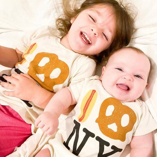 Cream t-shirt with hot dog and pretzel graphic above black NY text