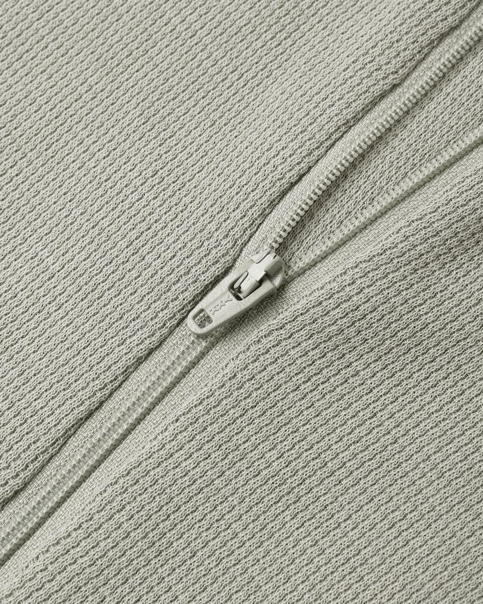 Close up of a Quincy Mae sage green textured fabric with a matching zipper