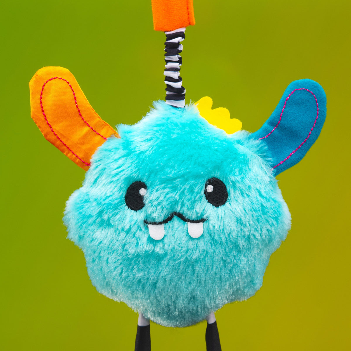 Sassy plush blue monster toy with orange and blue ears and a striped hanging cord