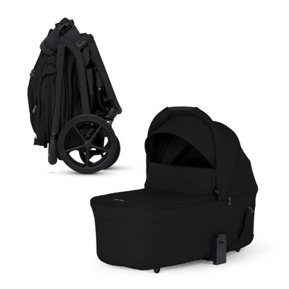 Onyx compact bassinet by Silver Cross, sleek black fabric, side view, with folded stroller frame and large wheels visible.