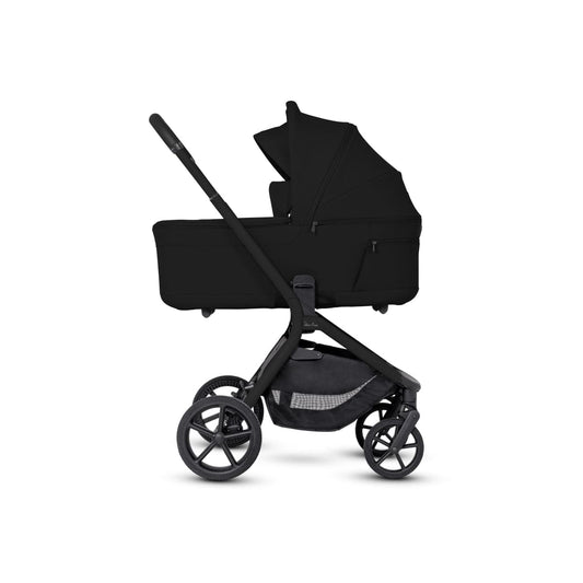 Onyx compact bassinet by Silver Cross, sleek black fabric, side view, with folded stroller frame and large wheels visible.