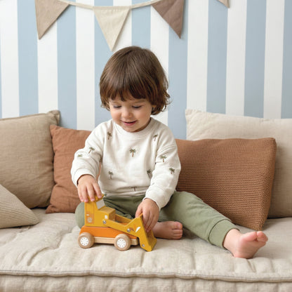 Toddler playing with a Speedy Monkey wooden toy construction vehicle on a cushioned bench