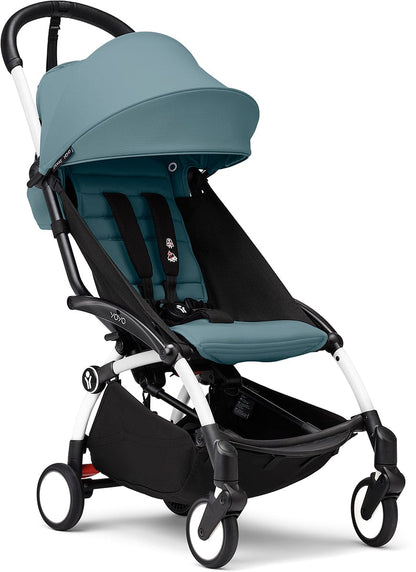 White and aqua ultra-compact stroller by Stokke, featuring quilted seat, black accents, and four wheels, shown in side view.