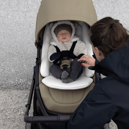 Baby sleeping in a Thule stroller with a beige canopy