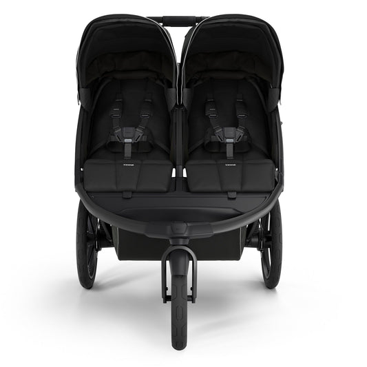 Black double jogging stroller by Thule with magnetic buckle, side view, large all-terrain wheels, padded seats, and white trim accents
