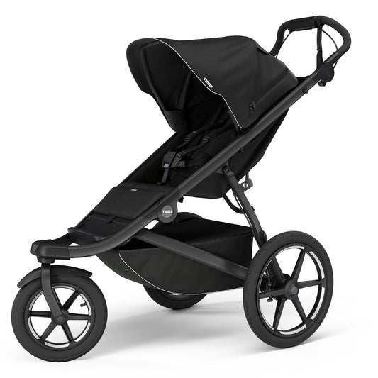 Black single jogging stroller by Thule with magnetic buckle, large all-terrain wheels, and adjustable canopy, side view