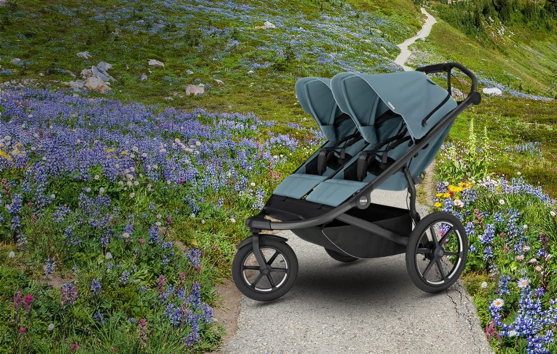 thule urban glide double in mid-blue in a mountain path with flowers - Albee baby exlusive color.