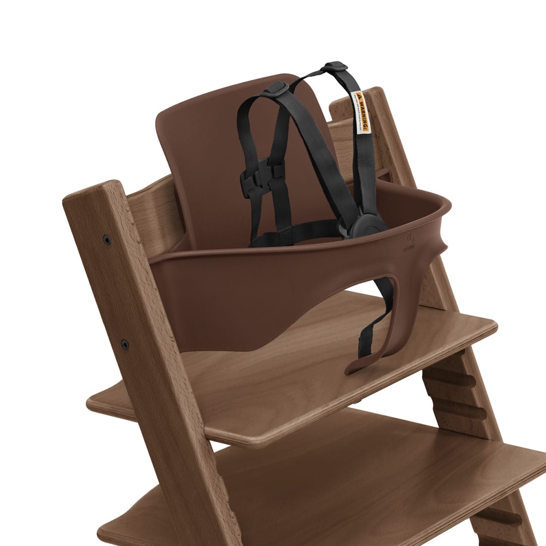 Stokke Tripp Trapp baby set in brown with black harness attached to wooden high chair